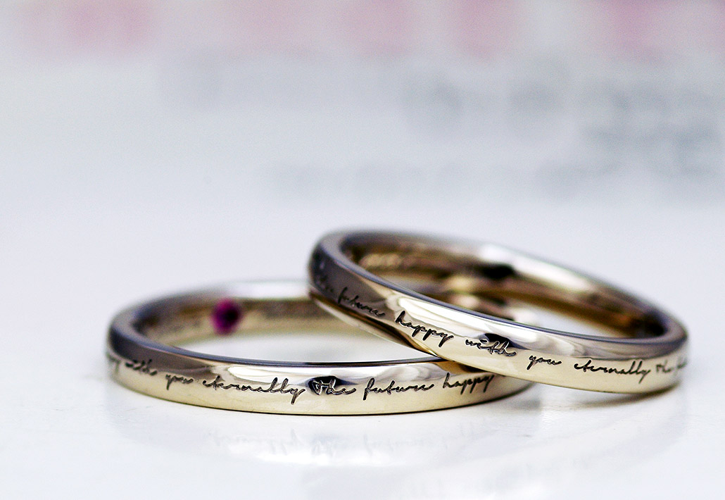 リングの表面に文字が刻印されたポージーリングデザインの結婚指輪（マリッジリング）