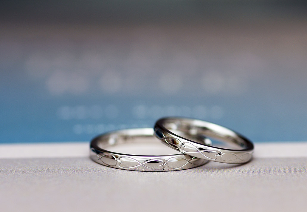プラチナ製のハートの手彫りデザインが並ぶシンプルな結婚指輪（マリッジリング）